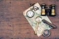 Vintage binoculars, compass, old map, magnifying glass, pocket watches, knife on wooden desk background