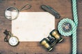 Vintage binoculars, compass, old paper, pocket watches, knife, rope, magnifying glass on wooden table background Royalty Free Stock Photo