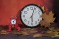 Vintage black alarm clock on autumn leaves. Time change abstract photo. Daylight saving time Royalty Free Stock Photo