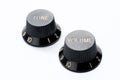 Two vintage black guitar volume and tone knobs on white background