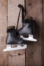 Vintage black ice skates for figure skating hanging on the background of wooden wall Royalty Free Stock Photo