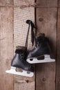 Vintage black ice skates for figure skating hanging on the background of wooden wall Royalty Free Stock Photo