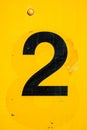 Vintage black number two painedt onto a rusty and yellow painted metal surface Royalty Free Stock Photo