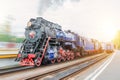 Vintage black steam locomotive train rush railway station. Concept of tourism is a retro journey by train. Royalty Free Stock Photo