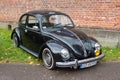 Vintage black VW Beetle parked near brick wall