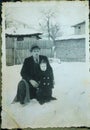 Vintage black and white photo of man and son in back garden in the snow 1950s.