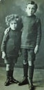 Vintage black and white photo of two young boys wearing shorts and boots, possibly brothers 1900s.