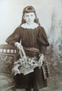 Vintage black and white photo of a young Victorian girl holding a basket of flowers 1880s - 1900s.