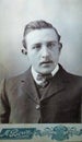 Vintage black and white photo of a young Victorian man with moustache wearing smart suit and slicked back hair 1880s - 1900s.