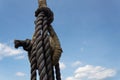 Vintage block and tackle with elaborate knots and wrapping on an old sailing vessel against a blue sky with clouds