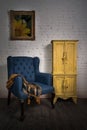 Vintage blue armchair, yellow cupboard and framed painting