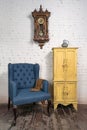 Vintage blue armchair, yellow cupboard, pendulum clock and orange scarf