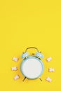 Vintage blue blank alarm clock on a yellow background with marskmallows