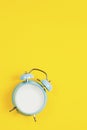 Vintage blue blank alarm clock on a yellow background