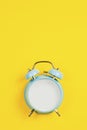 Vintage blue blank alarm clock on a yellow background