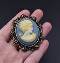 Vintage blue cameo brooch on a woman's hand, old retro jewelry Royalty Free Stock Photo