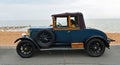 Vintage Blue Morris Oxford parked on seafront promenade beach and sea in background.