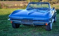 Vintage blue sports car convertible by a pasture at sundown.