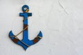 A vintage blue wood anchor on white plaster cement texture wall background, copy space