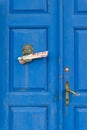 A vintage blue wooden double door with bronze knocker and newspapers Royalty Free Stock Photo