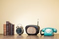 Vintage books, alarm clock, old radio, retro telephone on wooden table front blue background. Vintage style photo Royalty Free Stock Photo