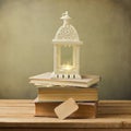 Vintage books and decorative lantern on wooden table. Christmas celebration