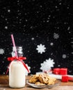 Vintage bottle of milk with red ribbon and santas cookies on wooden table over black background