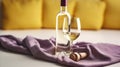 Vintage bottle of white wine with blank matte label and one glasses on purple napkin. Expensive bottle of chardonnay concept.