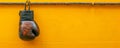 Vintage Boxing Glove Hanging Against Vibrant Yellow Wall Sports, Fitness, and Challenge Concept