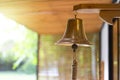 A vintage brass bell was hung on a brown wooden plank in the garden, with orange light effect, one can tell the time by ringing Royalty Free Stock Photo