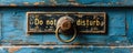 Vintage brass door knob on a distressed blue wooden door with a Do not disturb sign, conveying a request for privacy and Royalty Free Stock Photo