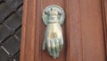 Vintage brass door knocker in the form of a hand with a ring on the finger on an old door Royalty Free Stock Photo