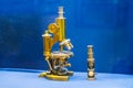 Vintage brass microscope on textured blue surface in antique pharmacy cabinet, soft lighting a Royalty Free Stock Photo