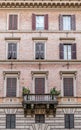 A vintage brickwall building facade with a single balcony and windows pattern.