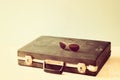 Vintage briefcase and glasses over wooden shelf. vintage filter.