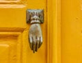 Vintage bronze hand shaped knocker on yellow door