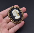 Vintage gold cameo brooch on a woman's hand, old retro jewelry Royalty Free Stock Photo
