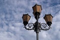 Vintage brown openwork five-horned lantern in a classic design against a blue sky covered with cumulus clouds Royalty Free Stock Photo