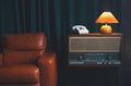 Vintage Brown leather armchair in loft design apartment..Old landline phone, vinil radio recorder and retro yellow lamp