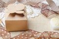 Vintage brown paper gift box with ribbon on burlap sack background.