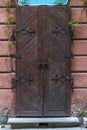 Vintage brown wooden door with forged hinges in an old city. Closed front door overgrown with ivy. Royalty Free Stock Photo