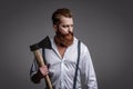 Vintage brutality guy with axe in retro suspenders. Brutal man in suspenders isolated on grey. Mature redhead man with