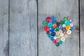 Vintage buttons in the shape of a heart on a wooden background