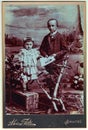 Vintage cabinet card shows children girl and boy, siblings posing in a photo graphic studio. Photo was taken in Austro-Hungarian