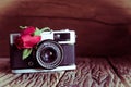 Vintage camera with roses on old wood background.