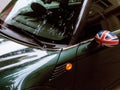 Vintage car detail, concept of British Patriotism shown as flag on mirror, trees in reflection windshield, body part Royalty Free Stock Photo