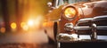 Vintage car headlights with beautiful blurred bokeh effect of vibrant sunset in the background Royalty Free Stock Photo