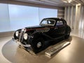 an old - fashioned car on display in a room with a spotlight and wall