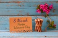 Vintage card with phrase: 8 march happy womens day on wooden texture table next to purple bougainvillea flower. Royalty Free Stock Photo