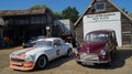Vintage cars parked outside repair shop, MG and Morris Traveller.